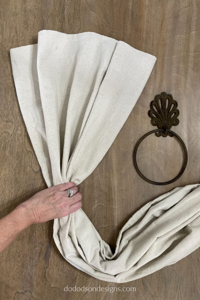 Using your hand, gather the drop cloth panel to make large pleats before pulling them through the hanger.