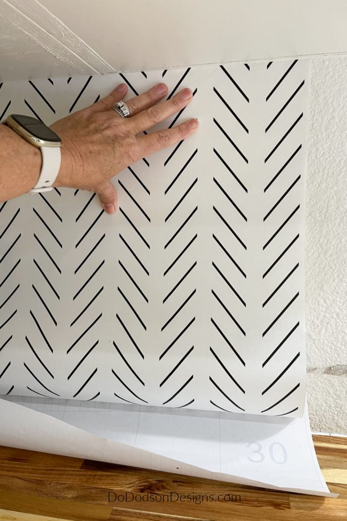 Start the application of the peel and stick wallpaper backsplash from the top, smoothing the paper as you work your way down with your hand.