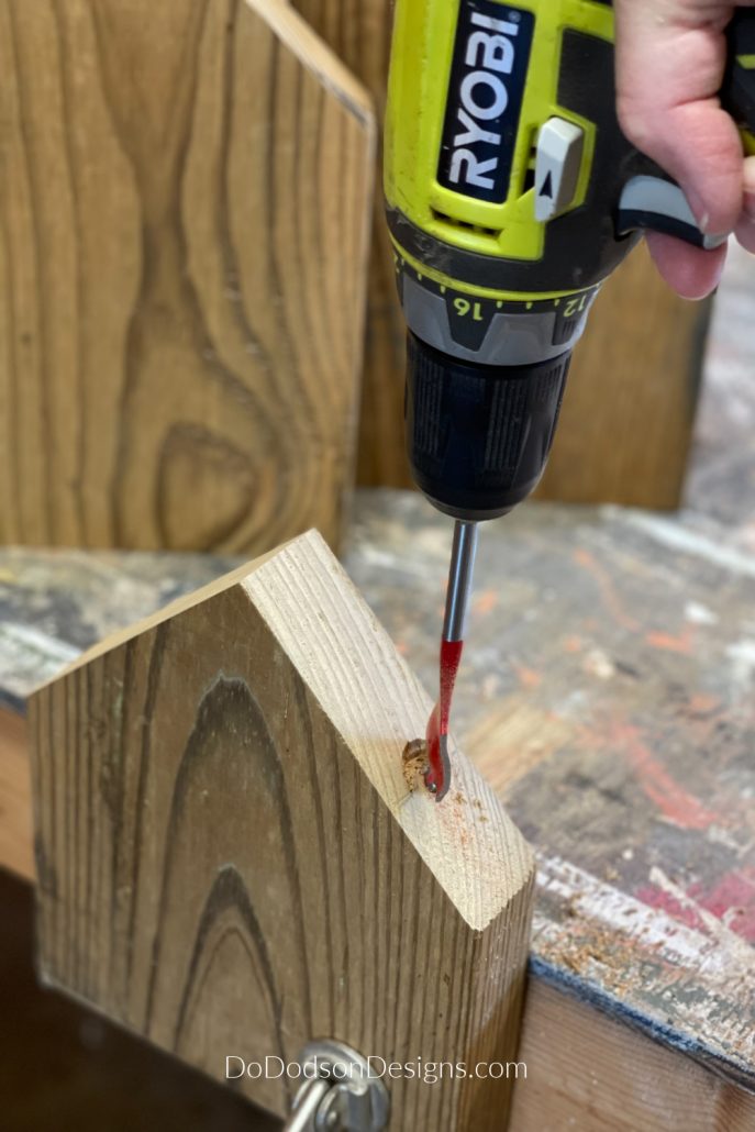With a spade wood bit and a drill, make a hole about 2 inches in depth at the top part of the "roofline" of the wood block houses.
