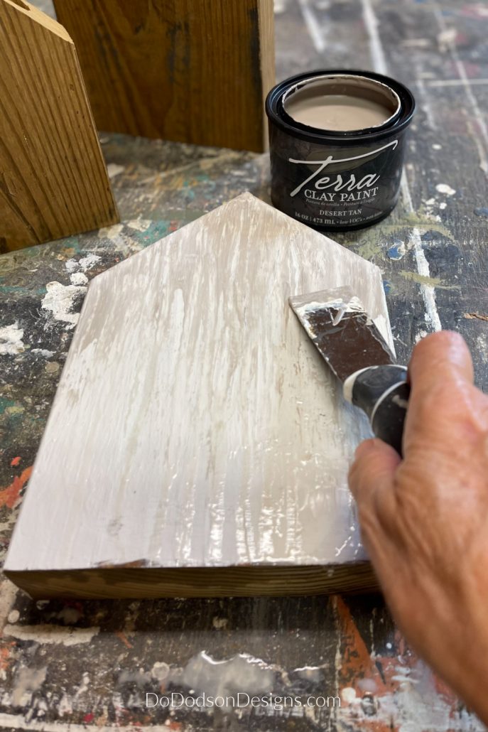 I used a paint scrapping tool to drag paint across my scrap wood block houses to create an amazing textured finish. 